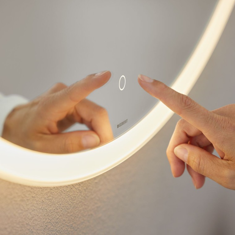 Hand operating touch sensor switch on Geberit Option Round mirror (© Geberit) Hand operating touch sensor switch on Geberit Option Round mirror (© Geberit)