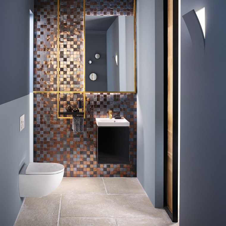 View into a modern guest bathroom with an Acanto WC and an Acanto washbasin in front of a mosaic back panel View into a modern guest bathroom with an Acanto WC and an Acanto washbasin in front of a mosaic back panel
