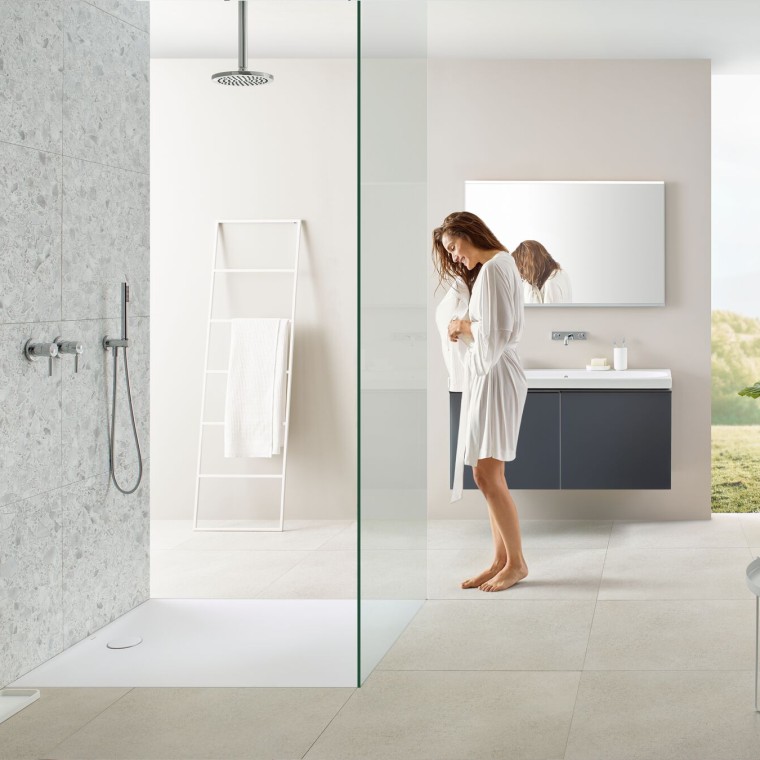 Woman in bathroom with walk-in shower and Geberit Olona shower tray