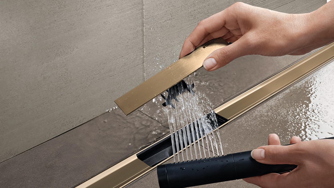 Woman removes the comb insert of the Geberit CleanLine shower channel and cleans it (© Geberit)