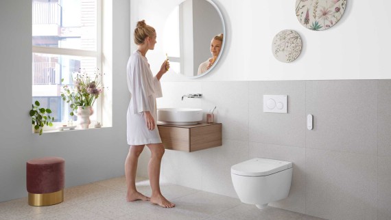 Woman in white bathroom with ceramic appliances and bathroom furniture