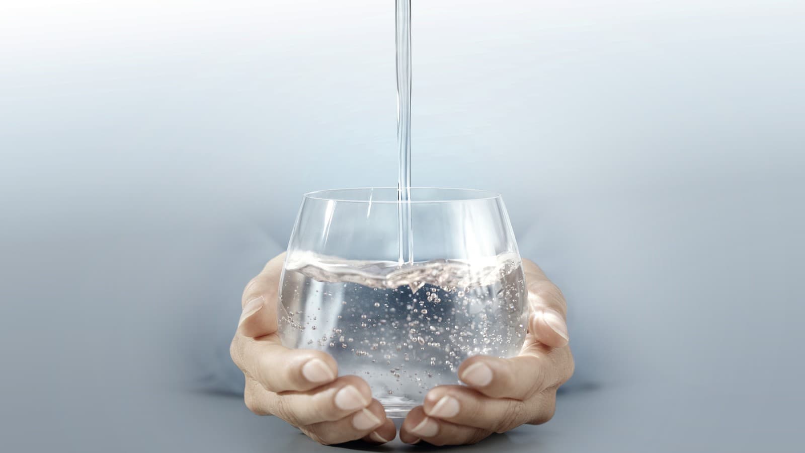 Person holding a glass of water in their hands Person holding a glass of water in their hands